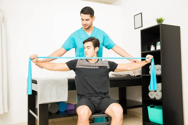 Physiothérapeute Aidant Patient Masculin Utilisant Bande Résistance Exercice Hôpital — Photo