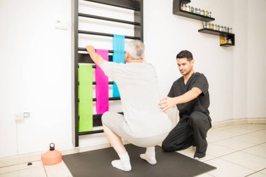 Klinikte genç fiziksel terapist yardımcı yapan olgun erkek ağız kavgası