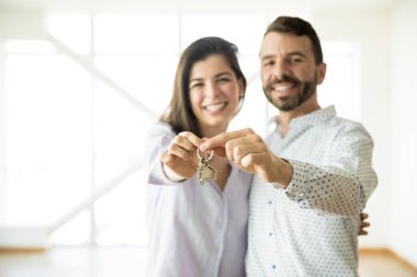 Portrait of smiling owners showing keys of their new apartment clipart