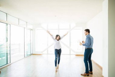 man looking at excited woman with arms raised in new house clipart