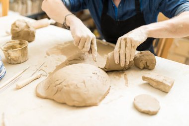 Erkek Potter kesme ve atölye masada kil Şekil aracını kullanarak kırpılmış görüntü