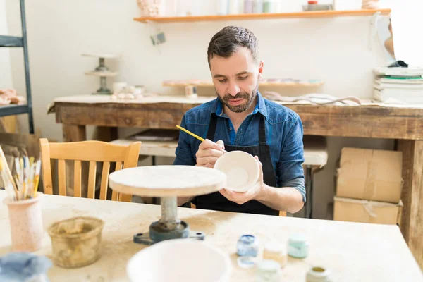 男艺术家装饰粘土碗与油漆在工作室表 — 图库照片