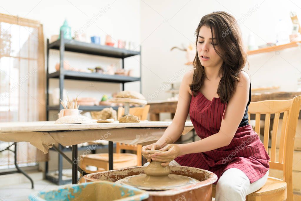 Beautiful mid adult woman learning the art of pottery in studio