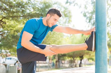 Sportif genç germe bacak ve kol kutup Park Yaz aylarında adam
