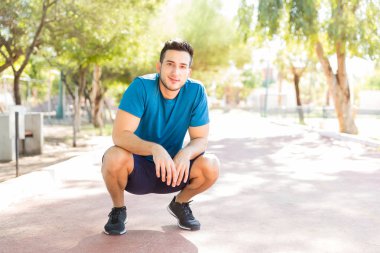 Kendine güvenen genç adam parkta güneşli günde çalıştırdıktan sonra mola tam uzunlukta portresi