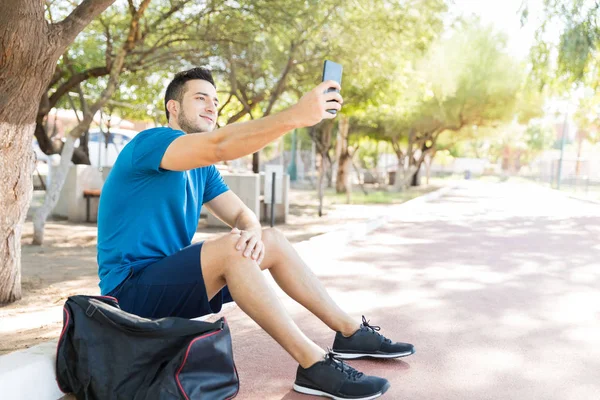 Parkta Otururken Cep Telefonuyla Selfie Alarak Yakışıklı Genç Atlet — Stok fotoğraf