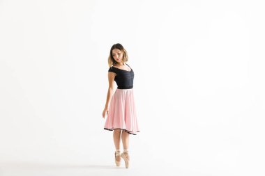 Beyaz arka plan üzerinde prova sırasında tiptoes üzerinde duran Genç balerin