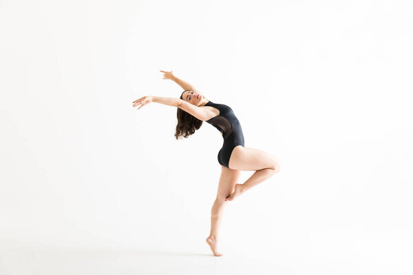 Fit young woman in ballet costume dancing over white background