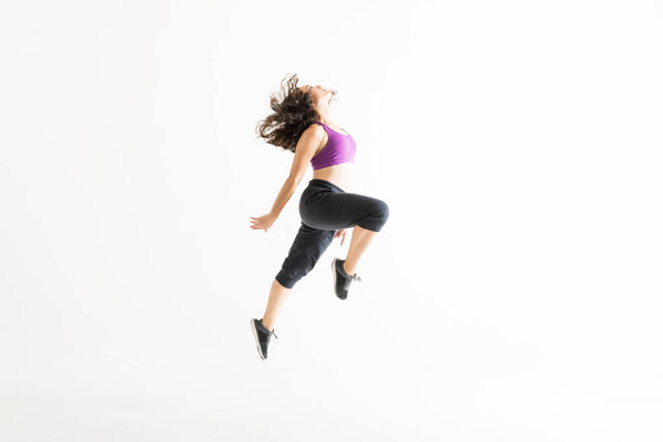 Side view of energetic woman performing jazz dance on white background