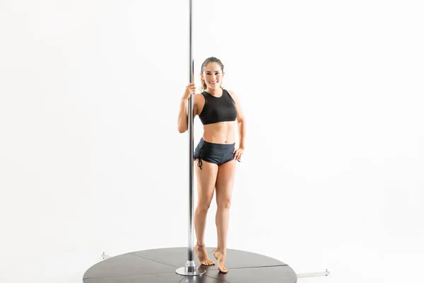 自信的女舞蹈家的肖像站立在杆反对白色背景时微笑 — 图库照片