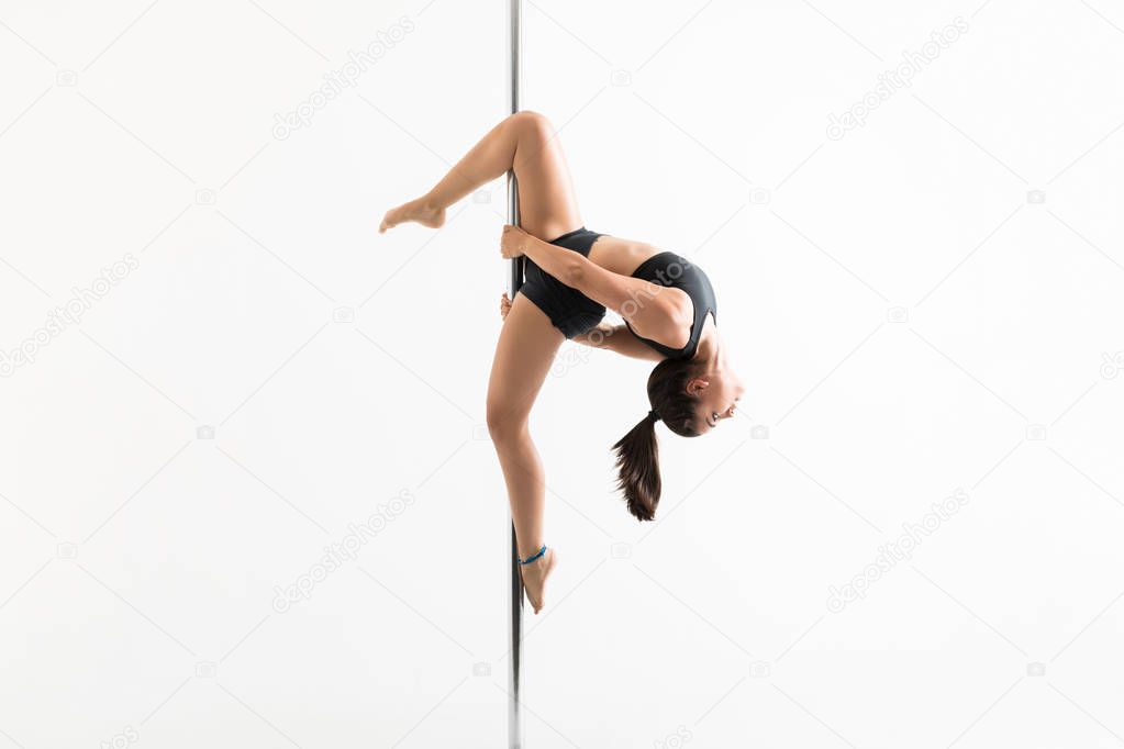 Side view of sensuous woman pole dancing over white background