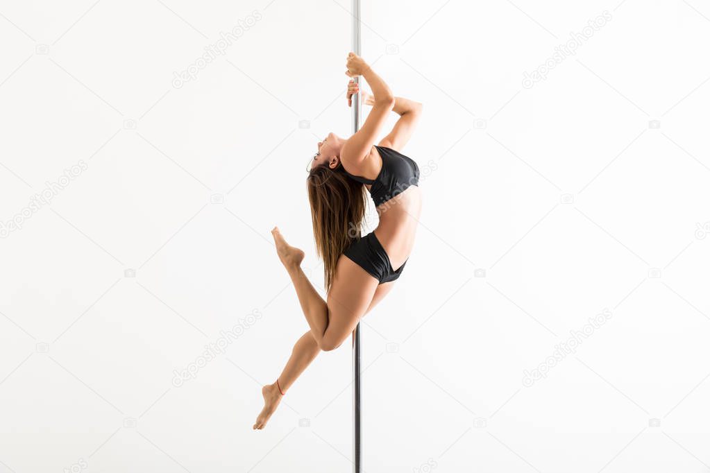 Full length of pole fitness expert flaunting dance moves in studio