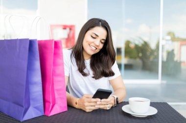 Güzel kadın müşteri manifatura Smartphone kafede masada