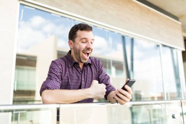 Şaşırmış adam alışveriş merkezi korkuluk üzerine eğilerek Smartphone cep telefonu ile indirim bildirimleri alma
