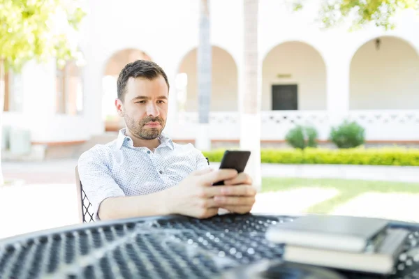 庭に座っているスマート フォンの重要な電子メールを読みながら集中して半ば成人男性 — ストック写真