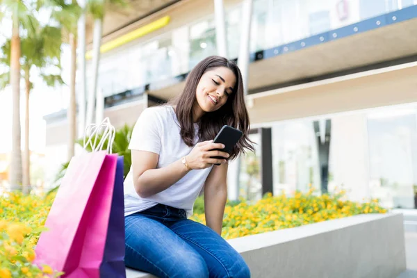 モールの外ショッピング バッグでの携帯電話のメッセージをチェックする女性 — ストック写真