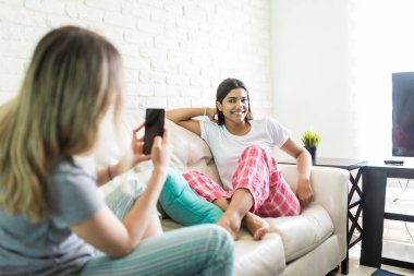 Güzel erkek arkadaş onu kanepeye pijama partisi sırasında fotoğraf çekimi sırasında poz