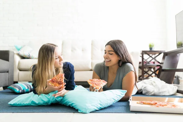 在家聚会时 年轻妇女拿着披萨片躺在地板上 — 图库照片