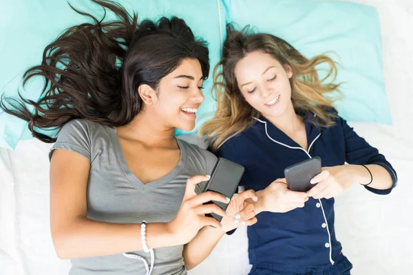 Översiktsbild Bästa Vänner Surfa Sociala Webbplatser Smartphone Liggande Sängen Hemma — Stockfoto