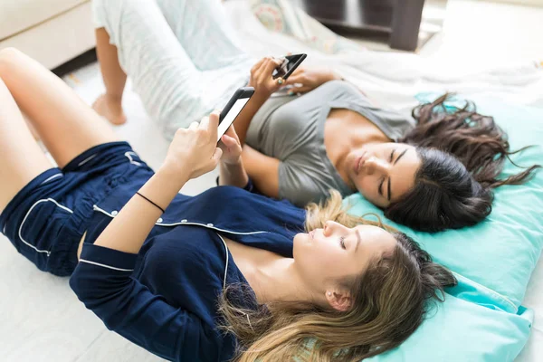 Mulheres Relaxadas Usando Mídias Sociais Telefones Celulares Cama Casa — Fotografia de Stock