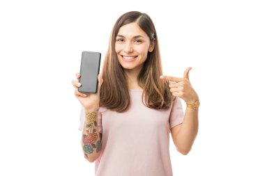 Beyaz arka plan üzerinde yeni smartphone vasıl işaret gülümseyen genç kadın portresi