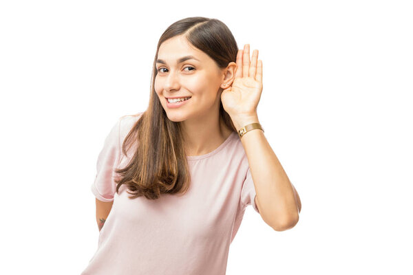 Улыбающаяся женщина пытается слушать что-то на белом фоне
