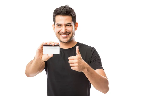 Retrato Jovem Sorridente Segurando Cartão Crédito Enquanto Gesticula Polegares Fundo — Fotografia de Stock