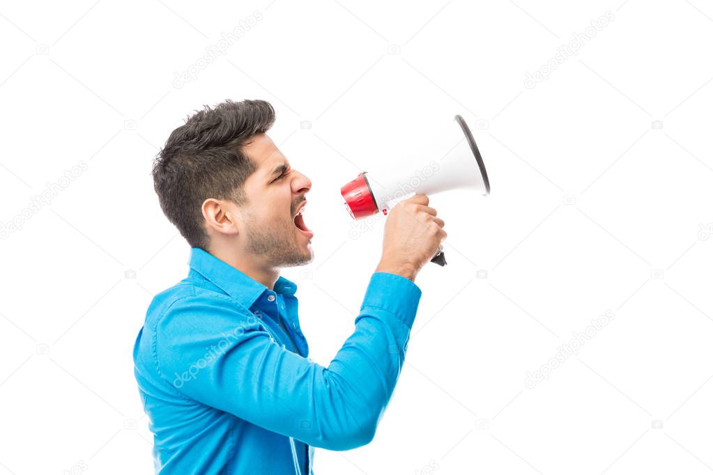 Side view of angry youth protesting while using megaphone against white background