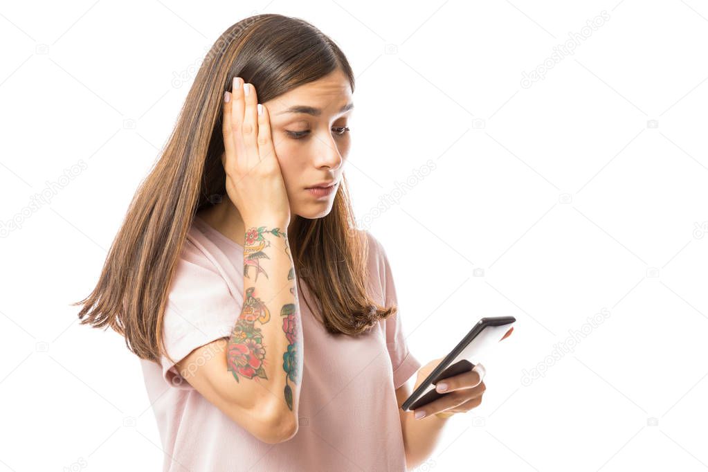 Upset woman reading bad news on smartphone against white background