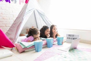 Küçük arkadaşlar aperatifler pijama partisi sırasında çadırda laptop film izlerken zevk