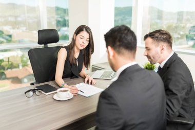 Kadın ofiste işadamları için kira sözleşmesi açıklayan emlakçı