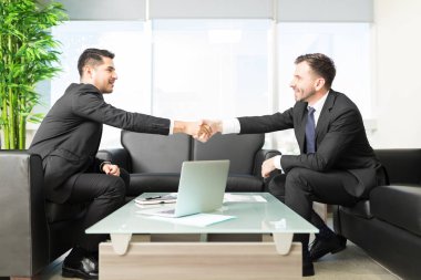 Business people shaking hands after closing deal in office clipart