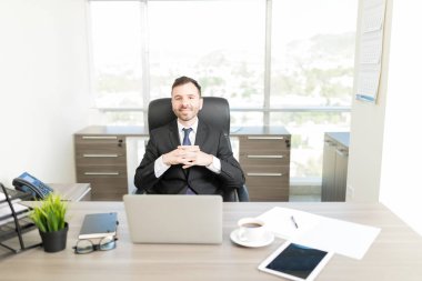 Yakışıklı kurumsal müdür ofis masasında sıktı elleri ile oturan portresi