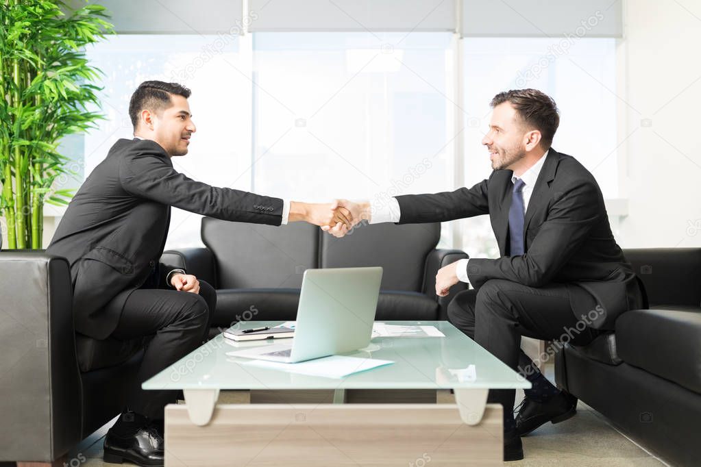Business people shaking hands after closing deal in office