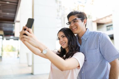 Şirin kız cep telefonuyla alışveriş merkezinde erkek arkadaşı ile Selfportrait alarak
