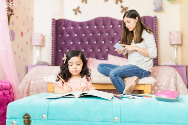 Schattig Klein Meisje Tekenen Terwijl Moeder Gebruikend Smartphone Slaapkamer — Stockfoto