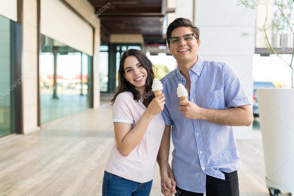 Portrait of happy and loving couple holding icecream cones in shopping center