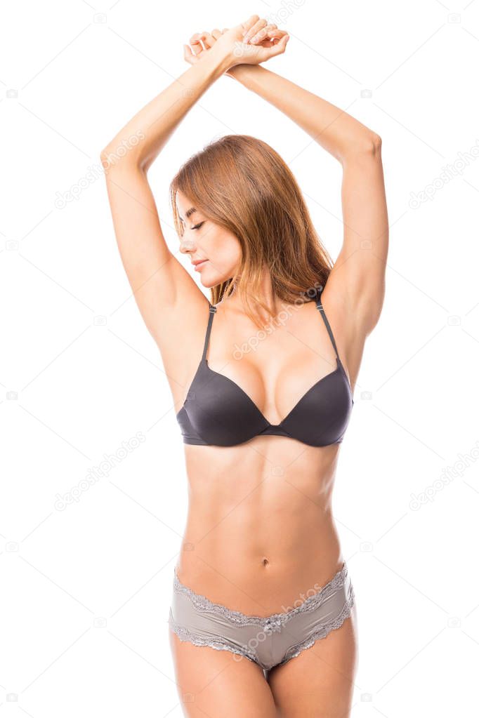 Attractive and fit woman wearing lingerie while showing armpits against white background