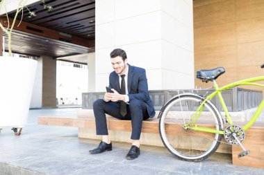 Erkek işveren tarafından Bisiklet ofis dışında otururken smartphone üzerinde e-posta yazma deneyimli