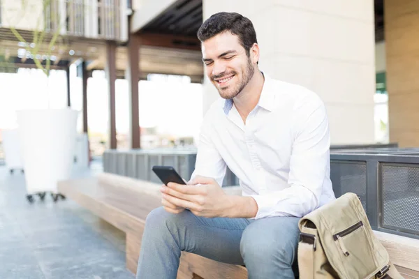 Ευτυχισμένος Ισπανόφωνος Επιχειρηματίας Χρησιμοποιώντας Κινητό Τηλέφωνο Ενώ Κάθεται Στον Πάγκο — Φωτογραφία Αρχείου