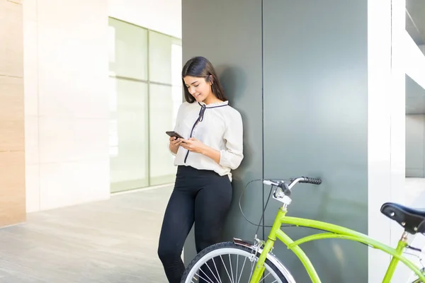 Kvinnlig Anställd Använder Mobila Applikationer Med Gröna Cykel Mot Kolumn — Stockfoto