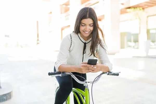 Улыбающаяся Очаровательная Латиноамериканка Велосипеде Ищет Информацию Мобильному Телефону Городе — стоковое фото