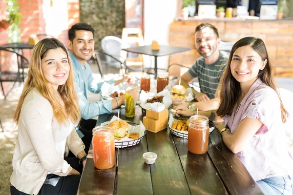 Group portrait of multiethnic friends smiling at outdoor restaurant table