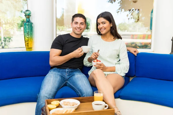 Retrato Jovem Casal Sorrindo Tomando Café Manhã Enquanto Sentado Sofá — Fotografia de Stock