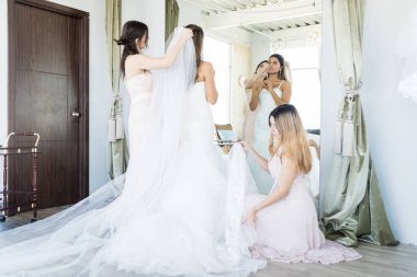 Beyaz nedime düğün töreni için giyinmeye genç güzel kadın yardım