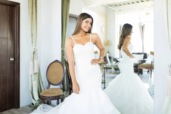 Portrait of mesmerizing woman in expensive wedding gown at bridal shop