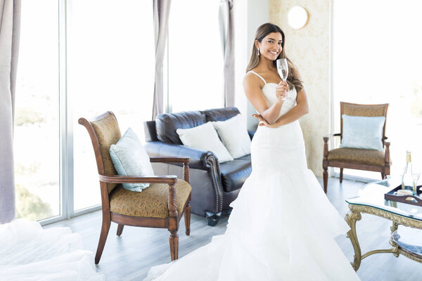 Good looking Latin bride smiling while enjoying champagne at a wedding venue
