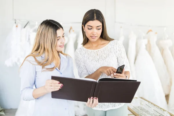 Joven Diseñador Novia Comparando Vestido Novia Catálogo Teléfono Inteligente Tienda — Foto de Stock