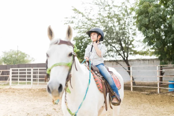 Menina Bonito Ajustando Capacete Enquanto Montando Cavalo Branco Rancho — Fotografia de Stock