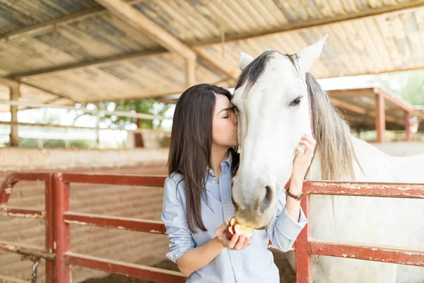 Gorgeous Brunette Kissing While Feeding White Horse Apple Stable — Stock Photo, Image